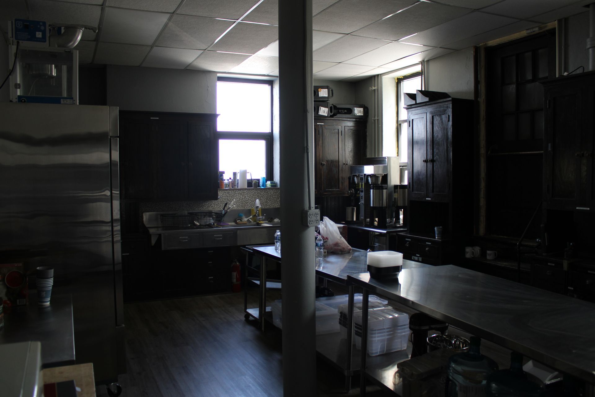 A dark kitchen with a stainless steel refrigerator and a sink