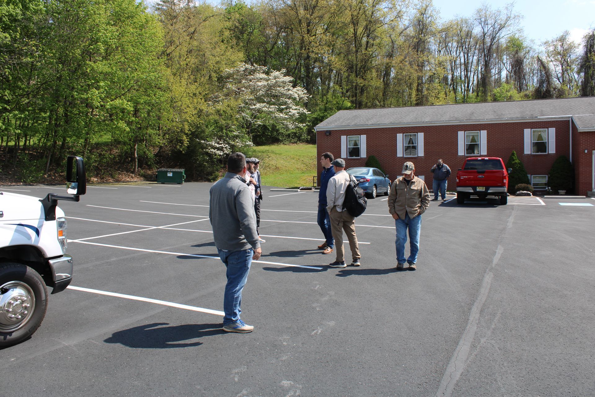A group of people standing in a parking lot in front of a brick building