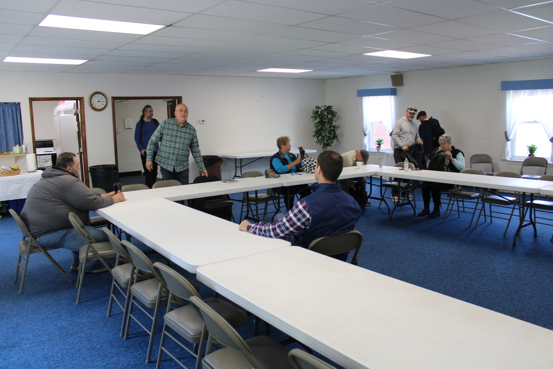 A group of people are sitting at long tables in a room.