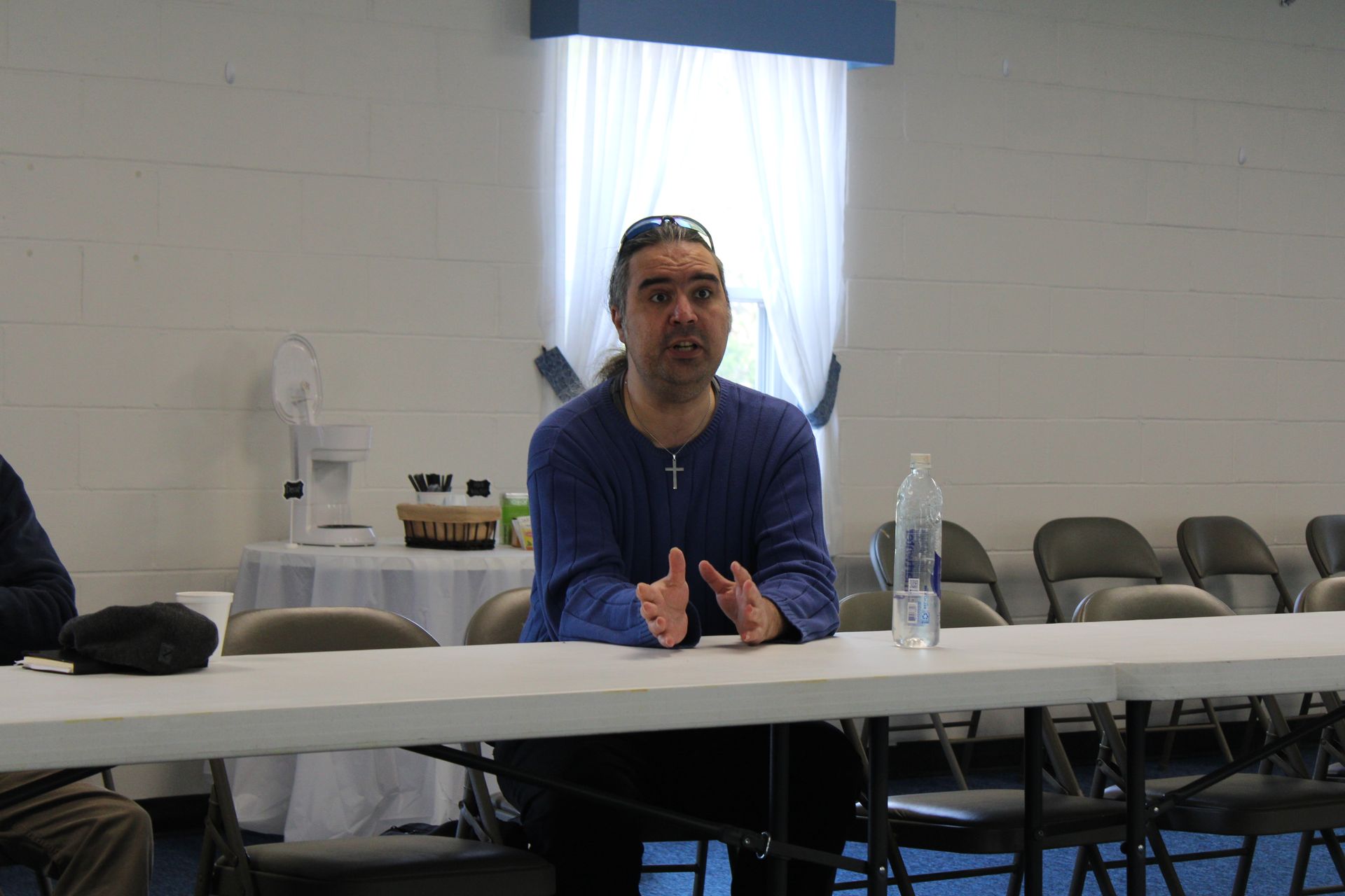 A man is sitting at a table with a bottle of water on it.