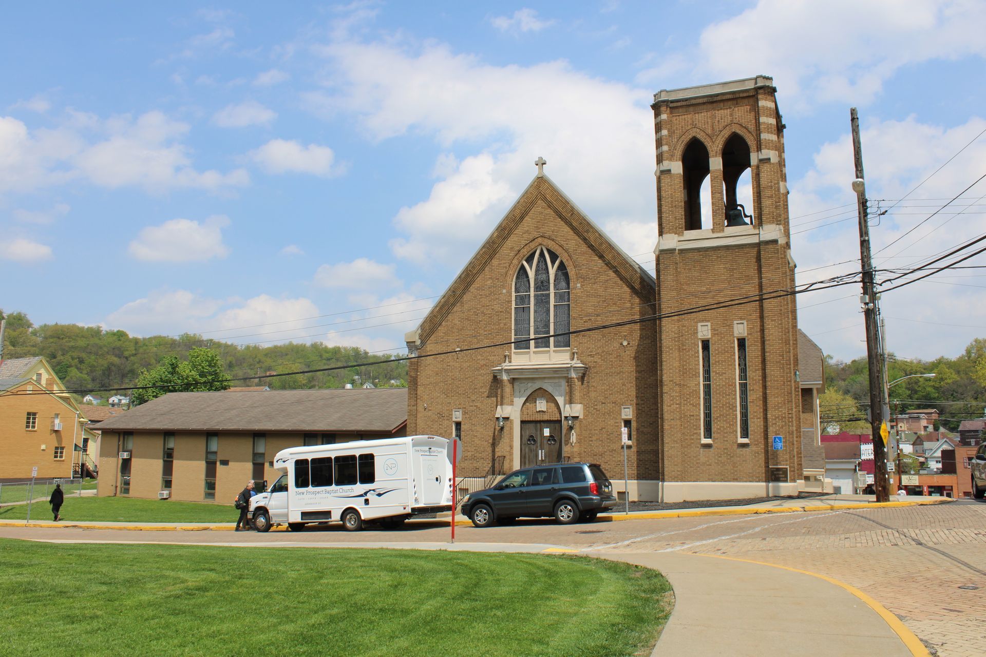 A white van is parked in front of a church