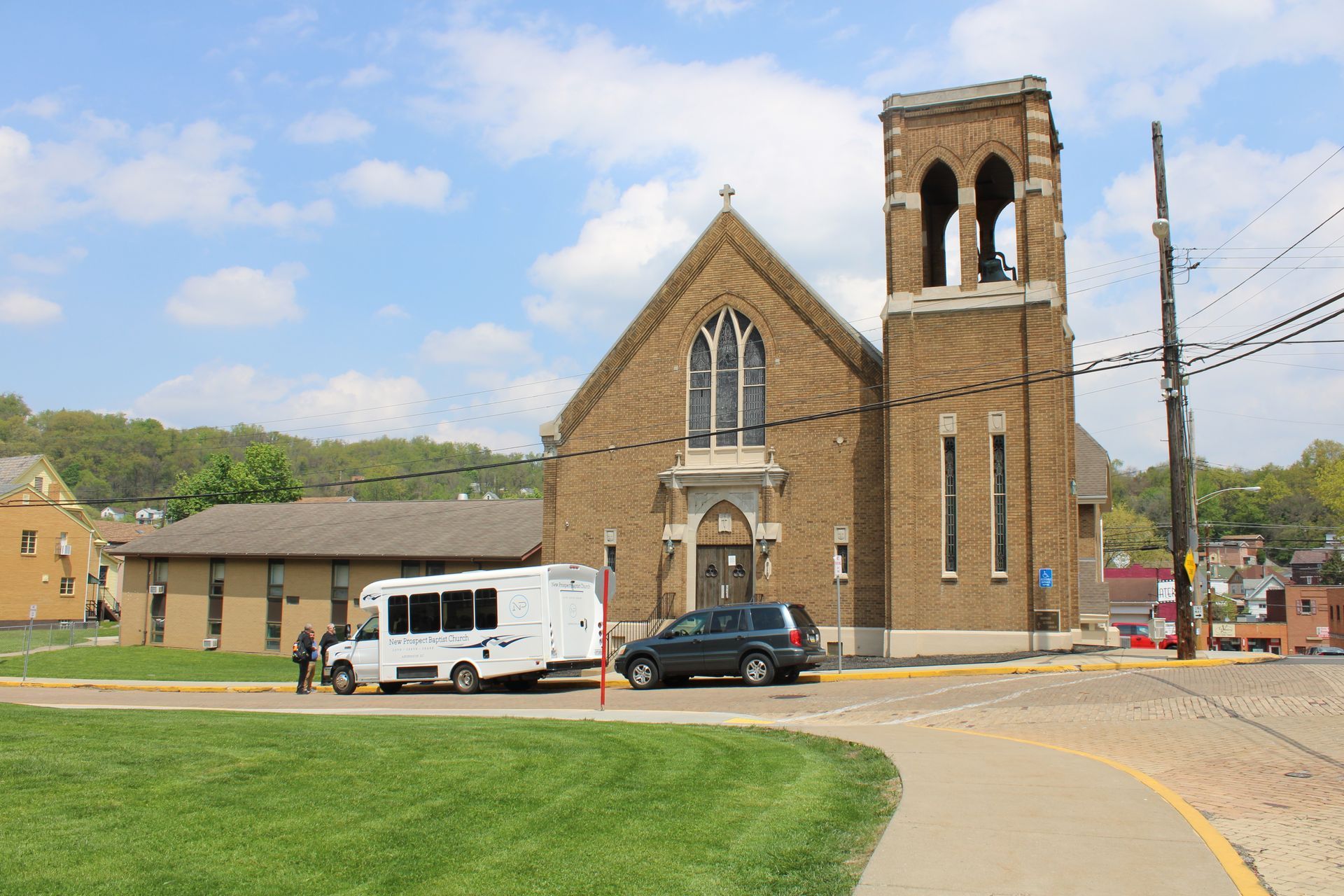 A white van is parked in front of a church
