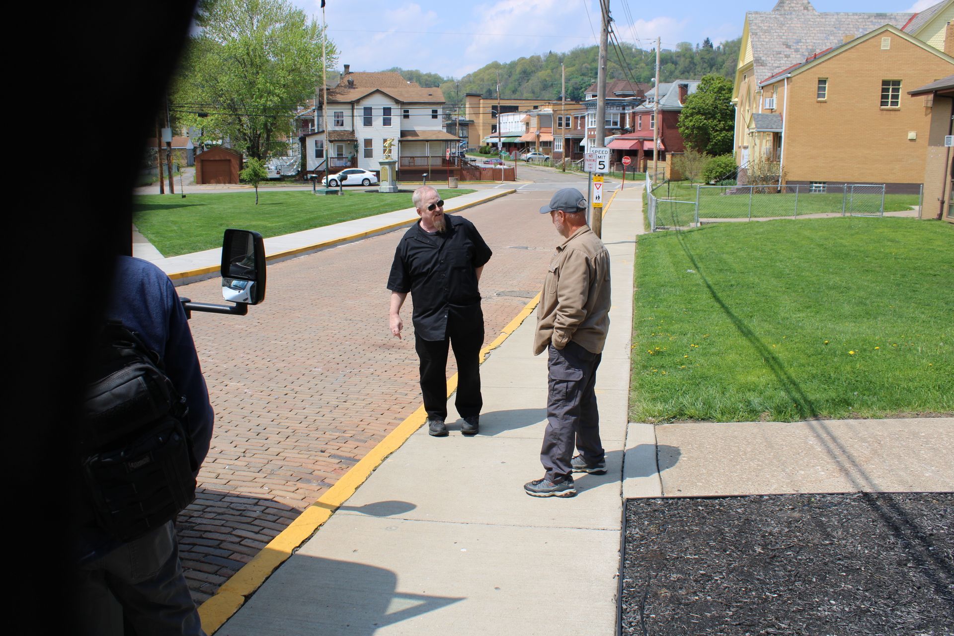 Two men standing on a sidewalk talking to each other