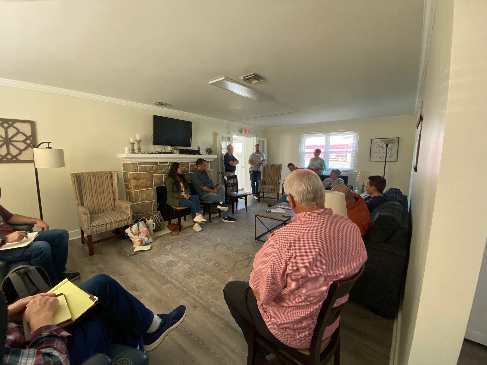 A group of people are sitting around a table in a living room.