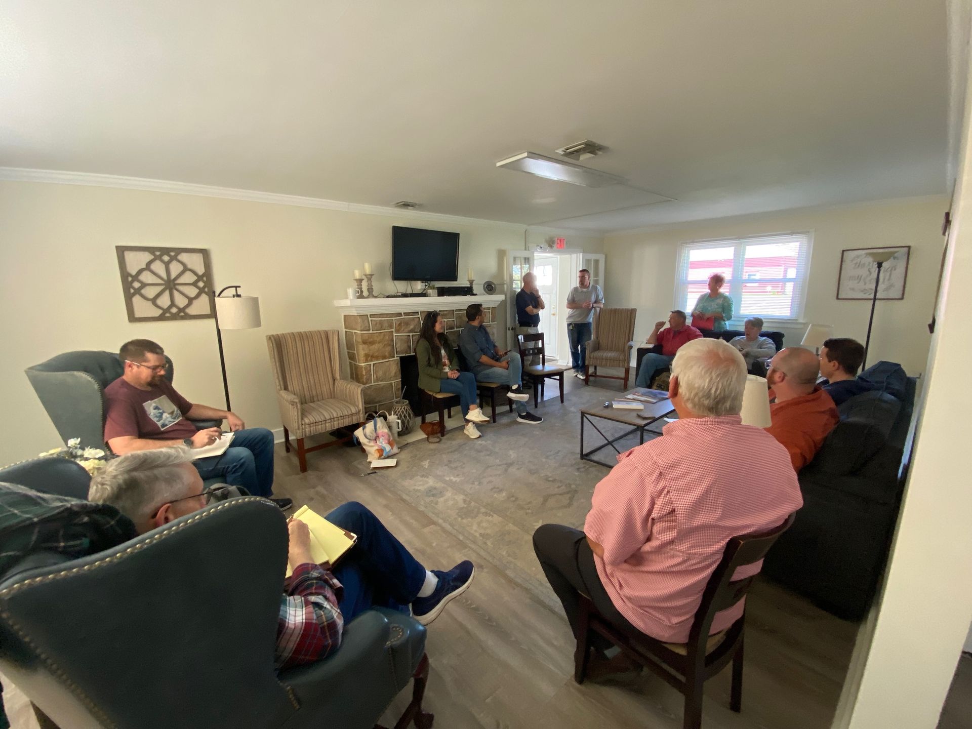 A group of people are sitting in chairs in a living room.