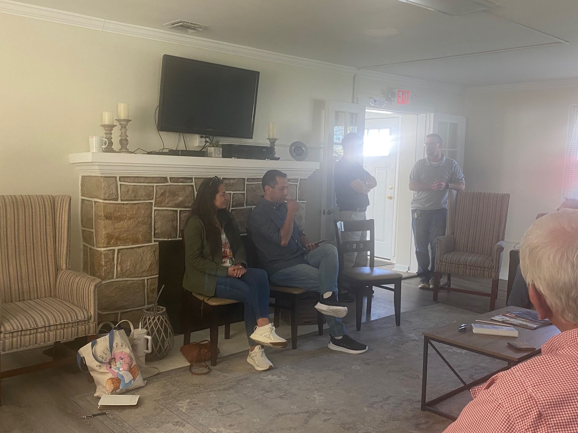 A group of people are sitting in a living room in front of a fireplace.