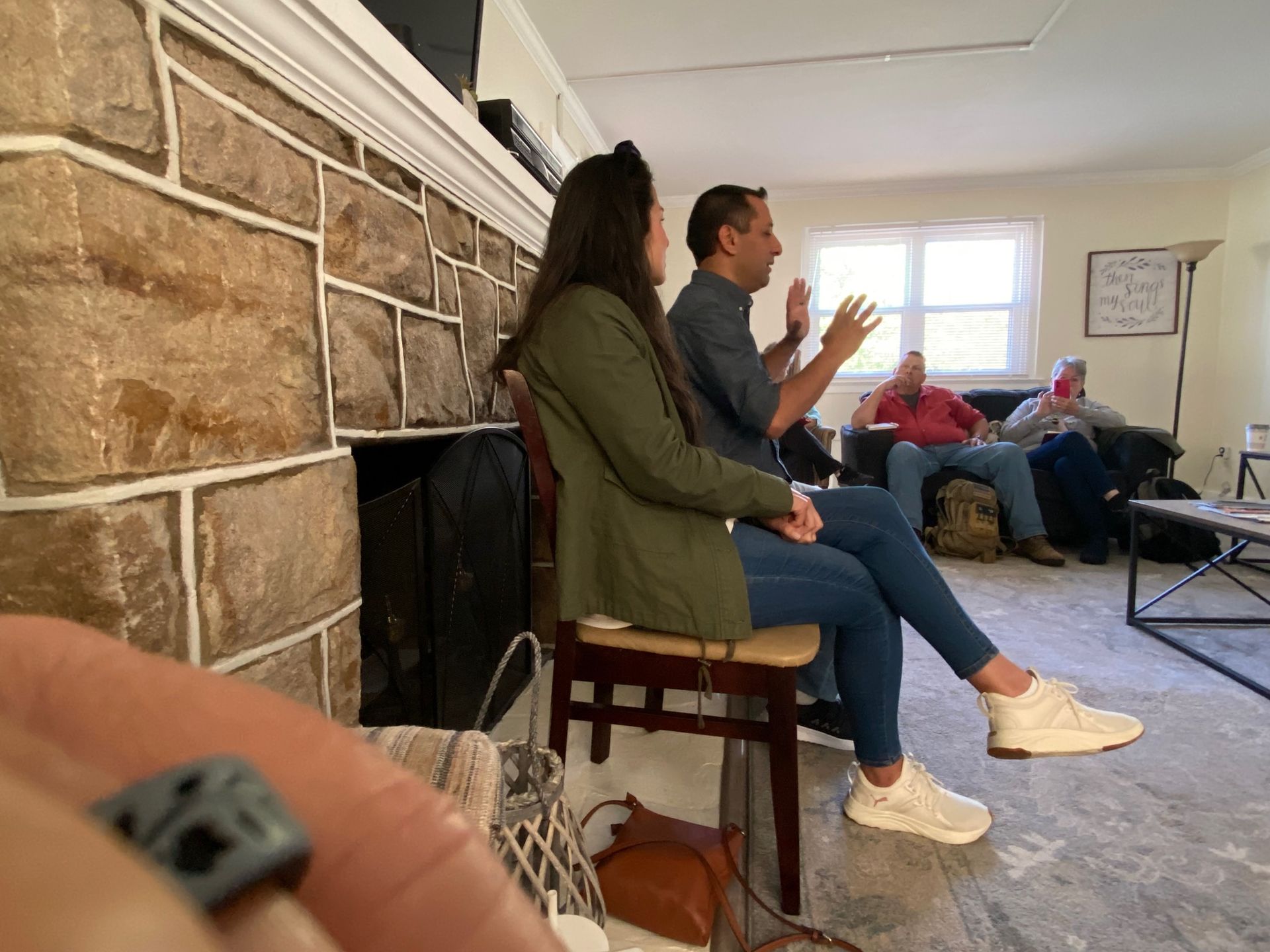 A group of people are sitting in a living room talking to each other.