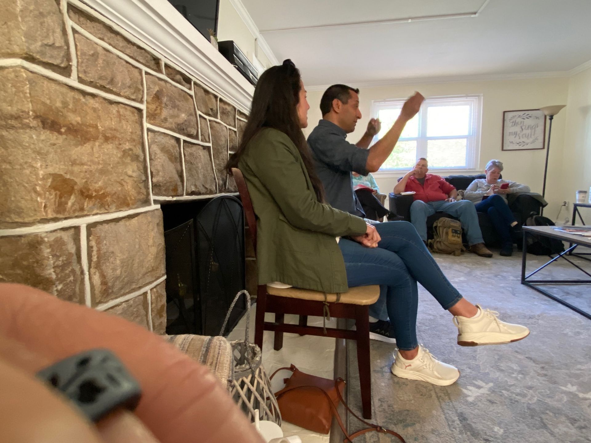 A group of people are sitting in front of a fireplace in a living room.