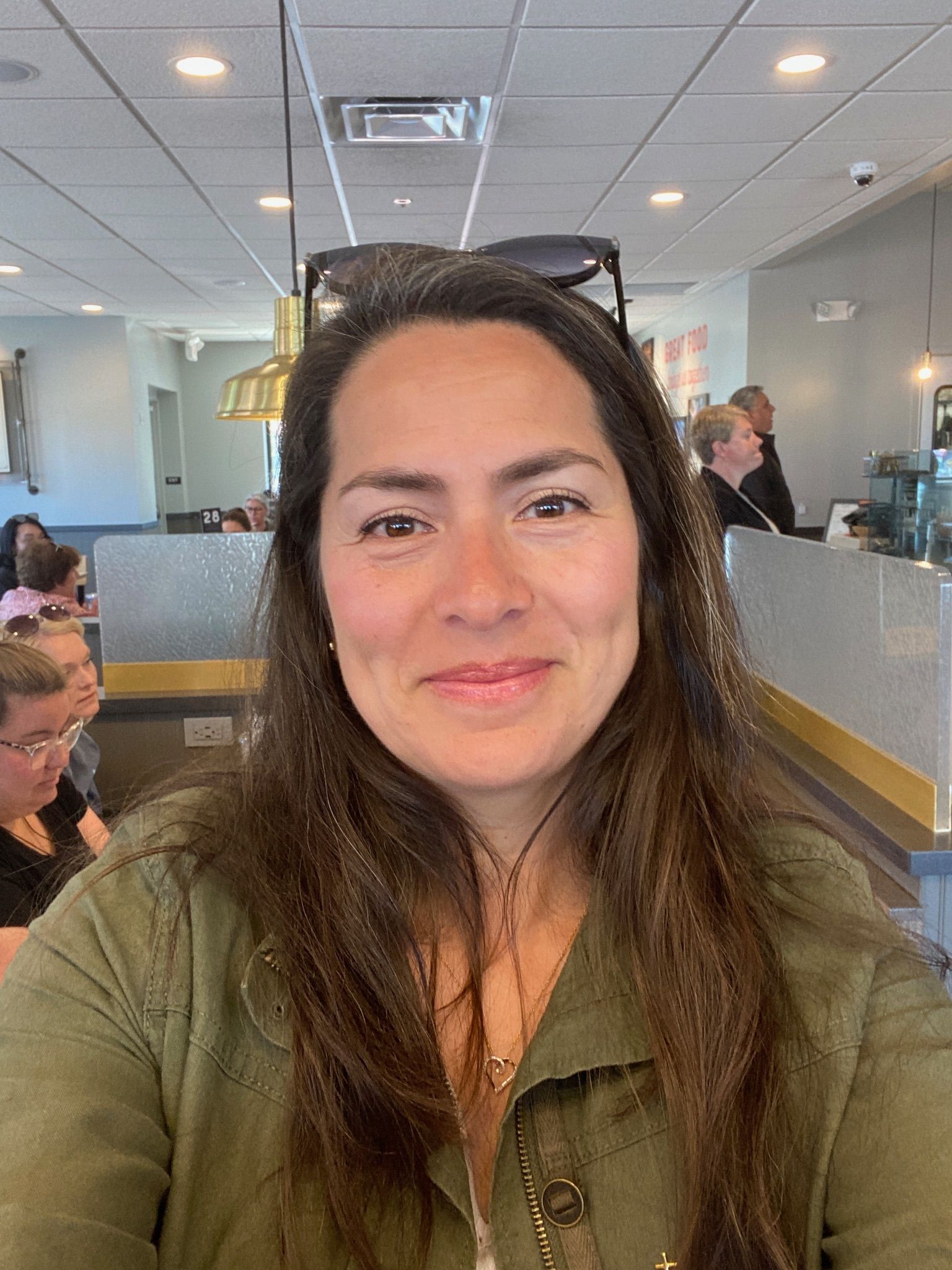 A woman with long hair is sitting at a table in a restaurant.