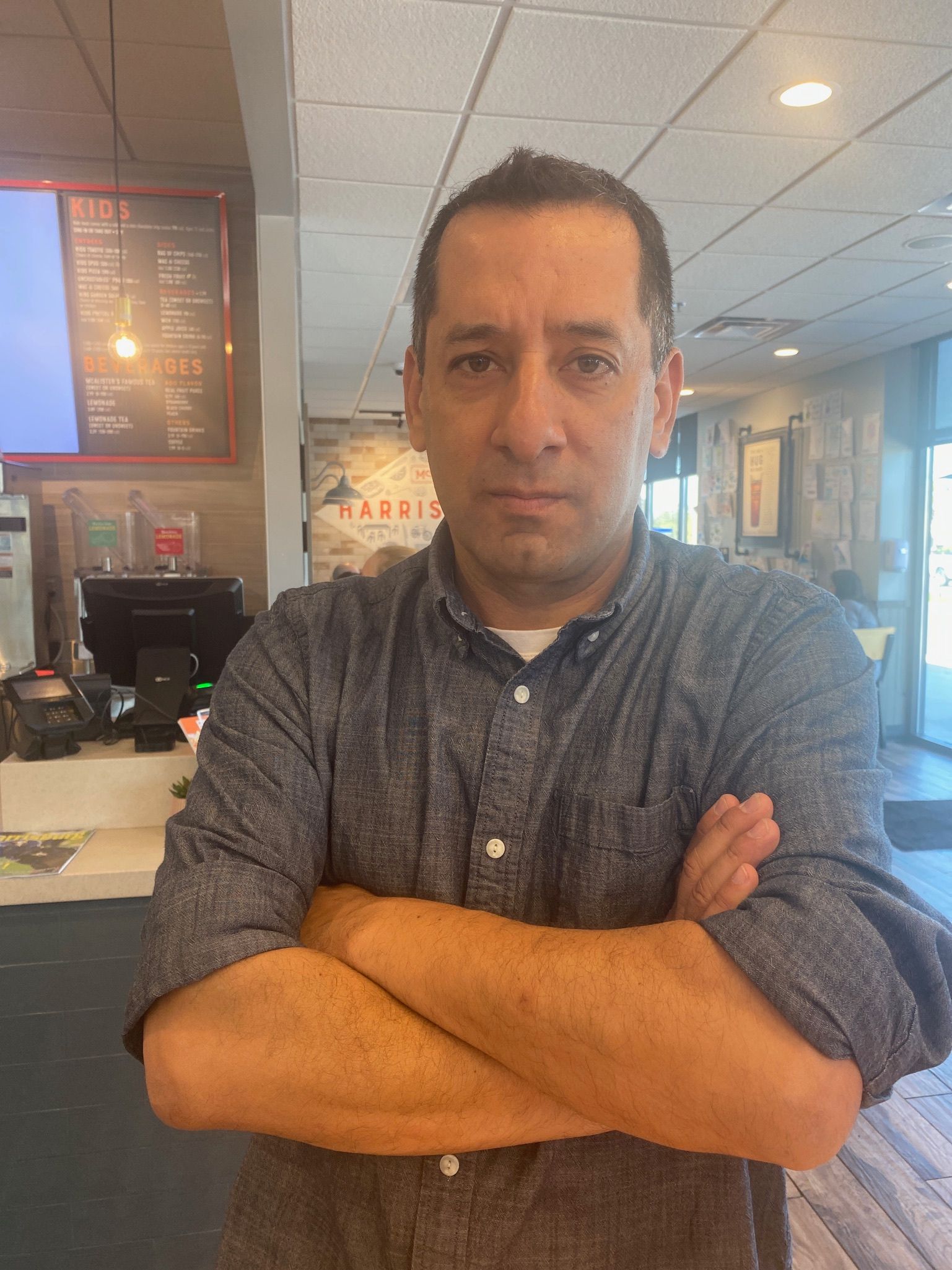 A man is standing with his arms crossed in a restaurant.
