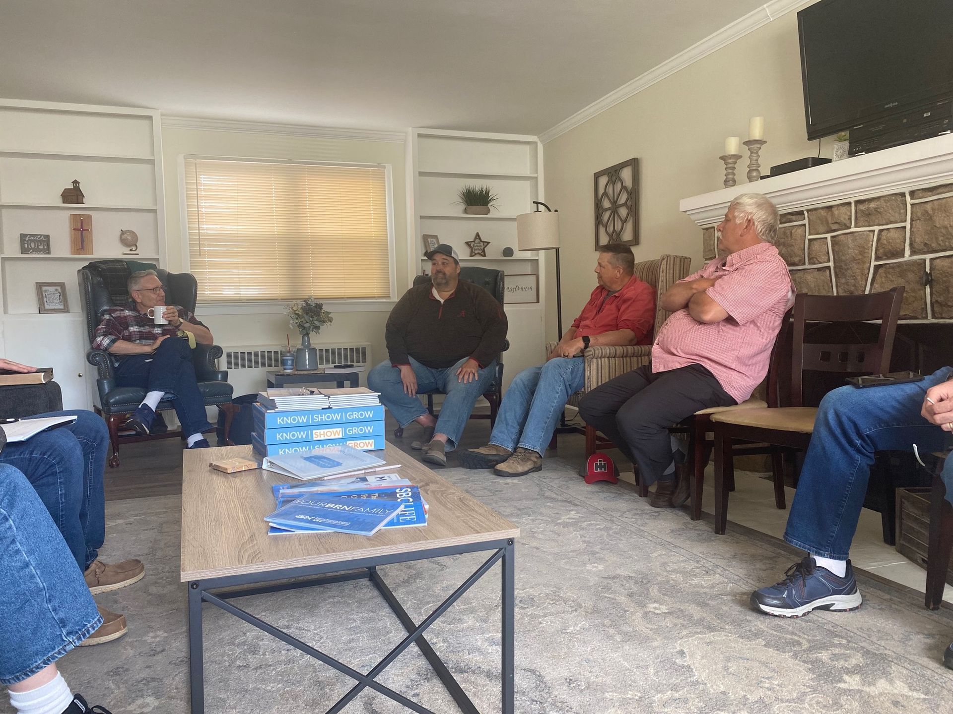 A group of men are sitting around a table in a living room.