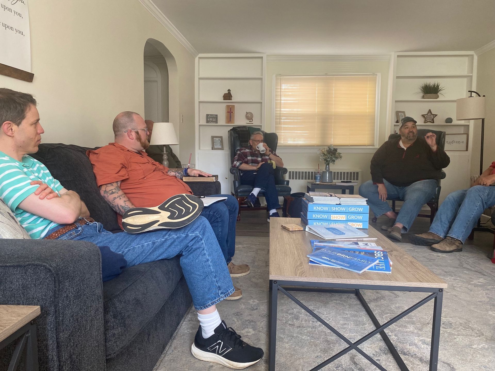 A group of people are sitting around a coffee table in a living room.