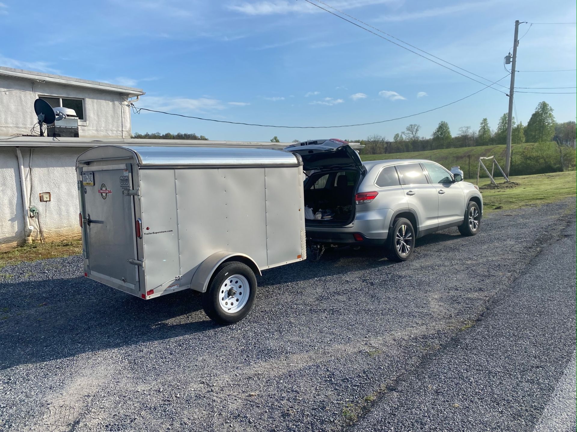 A car is towing a trailer on a gravel road.