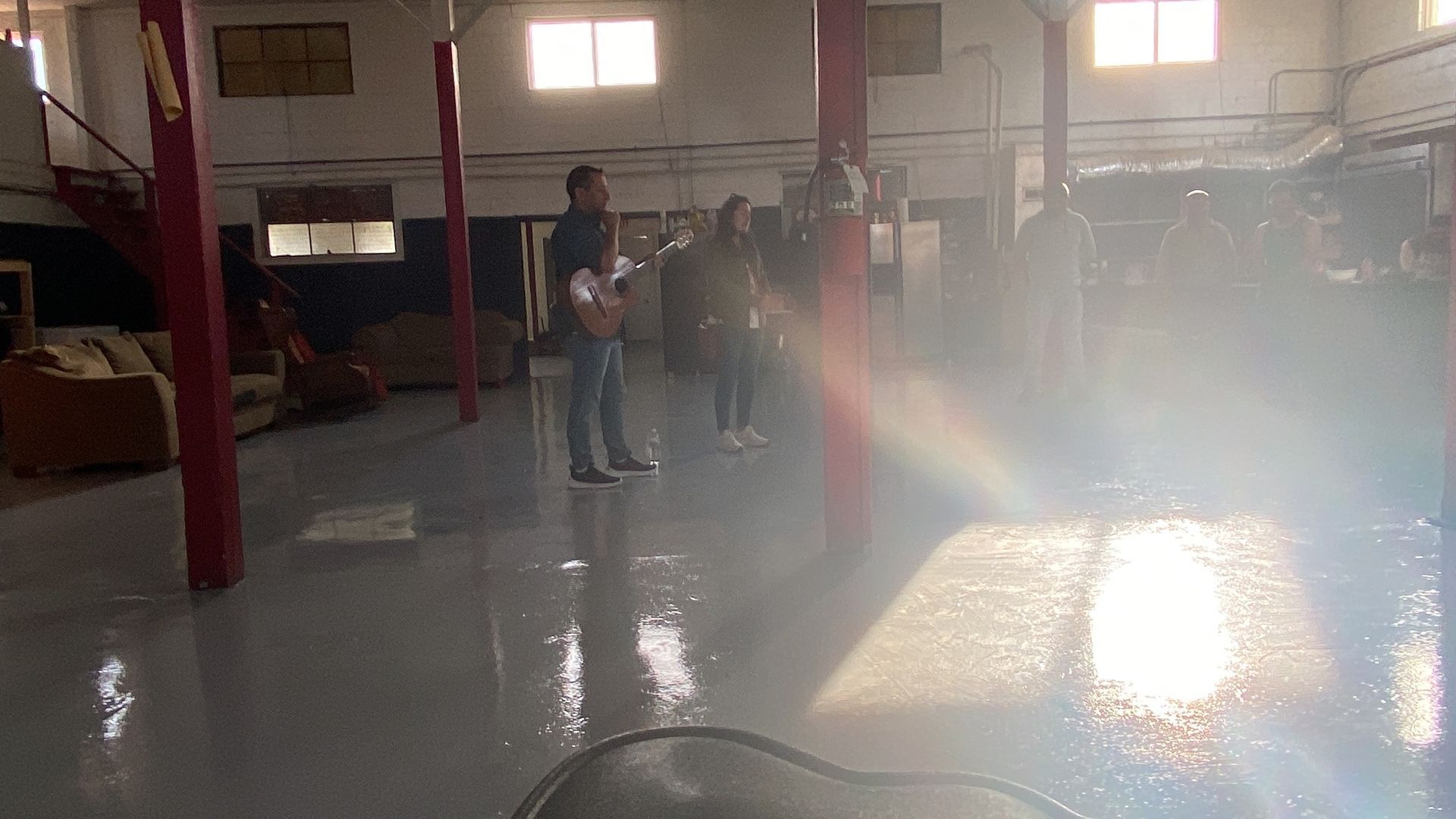 A man is standing in a room with a hose spraying water on the floor.