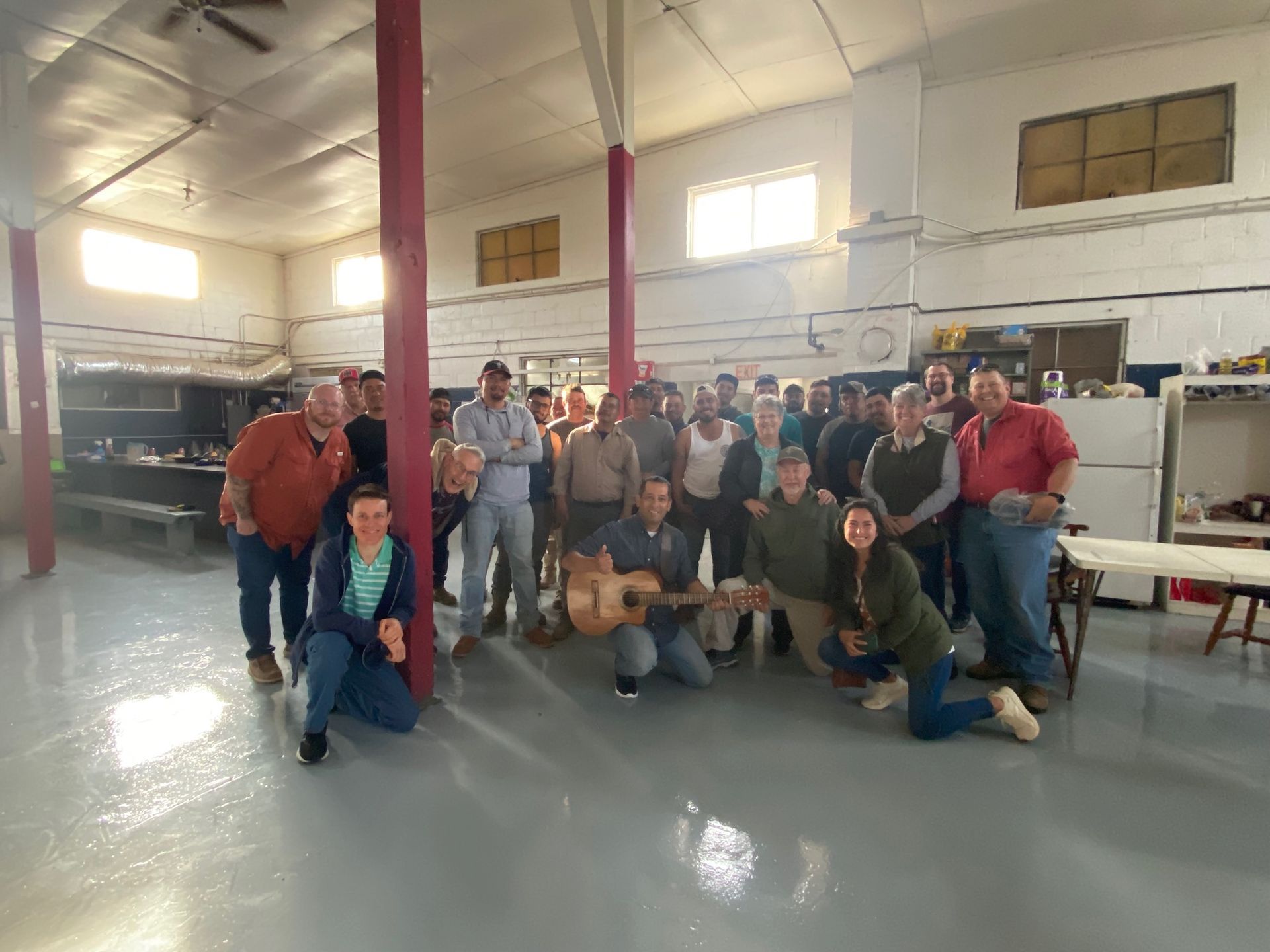 A group of people are posing for a picture in a room with a guitar.