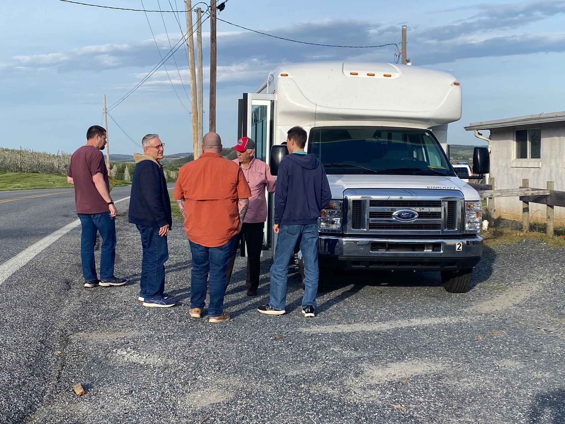 A group of people are standing in front of a white van.