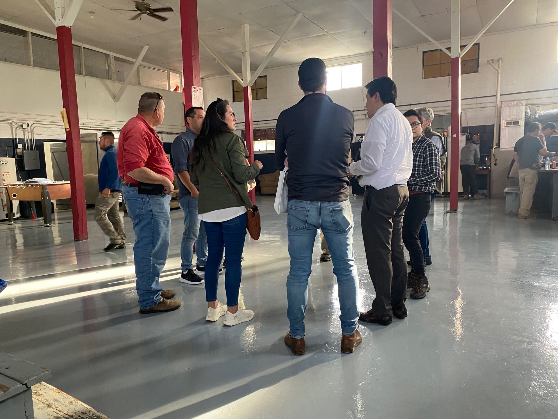 A group of people are standing in a room talking to each other.