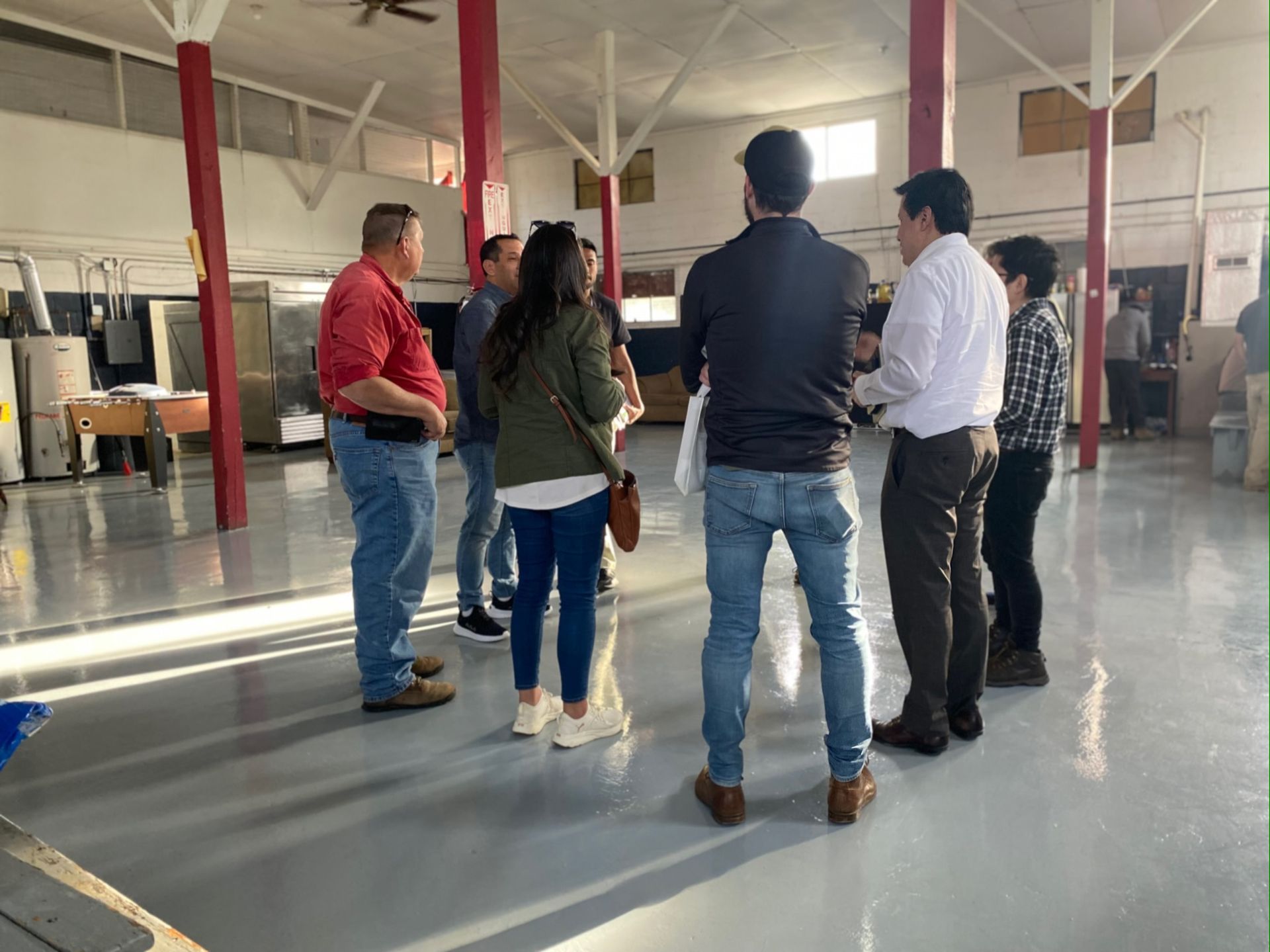 A group of people are standing in a room talking to each other.