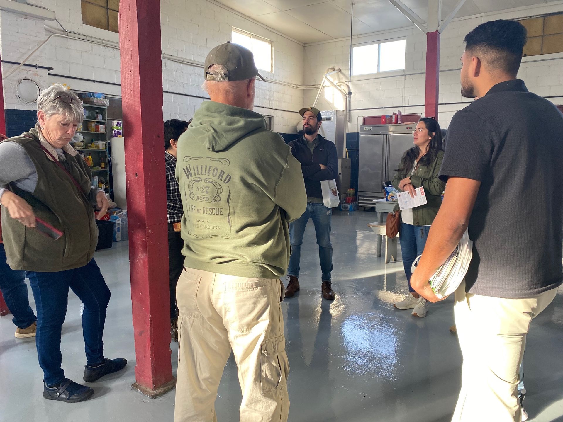 A group of people are standing in a room talking to each other.