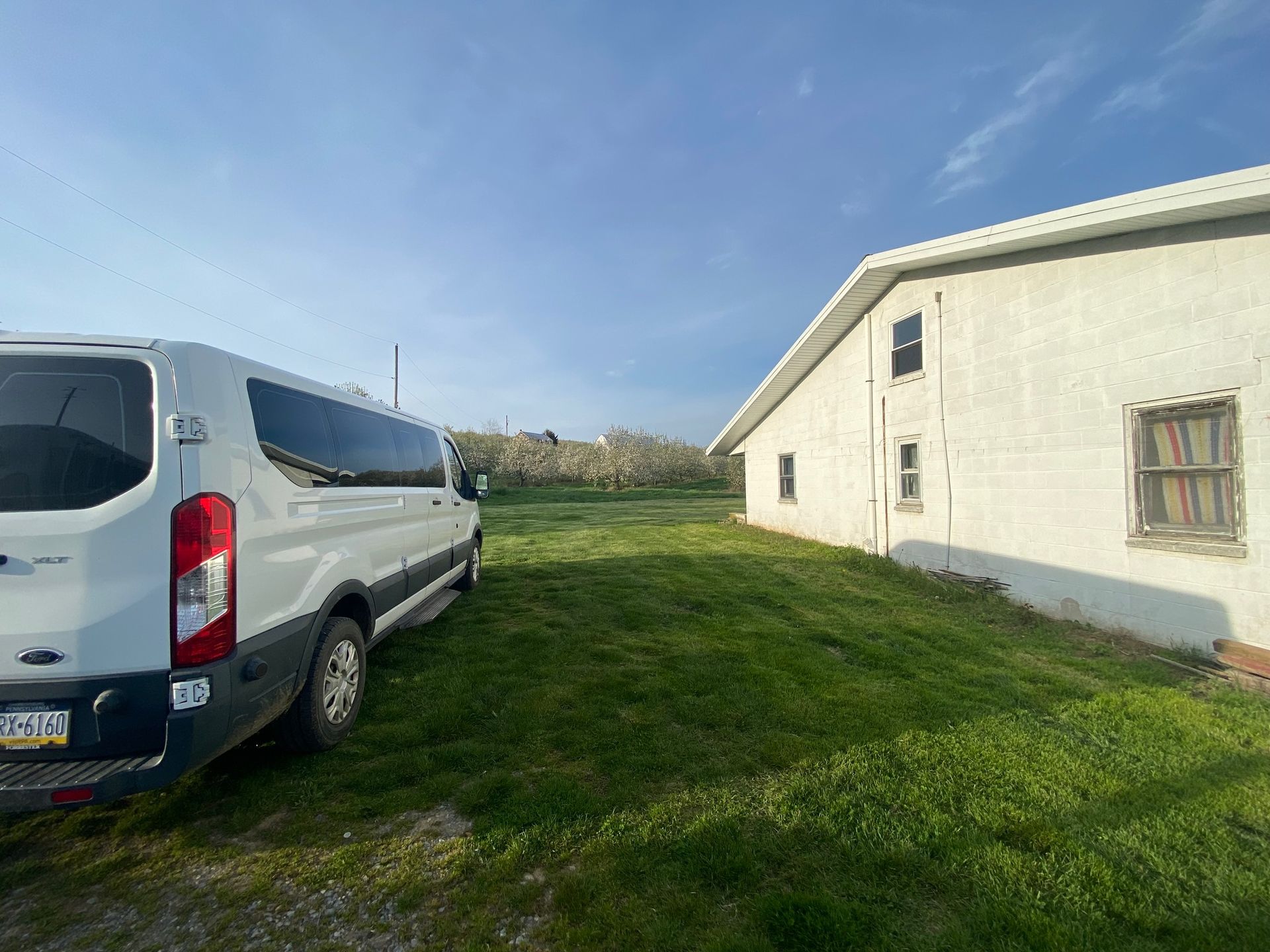 A white van is parked in front of a white building.