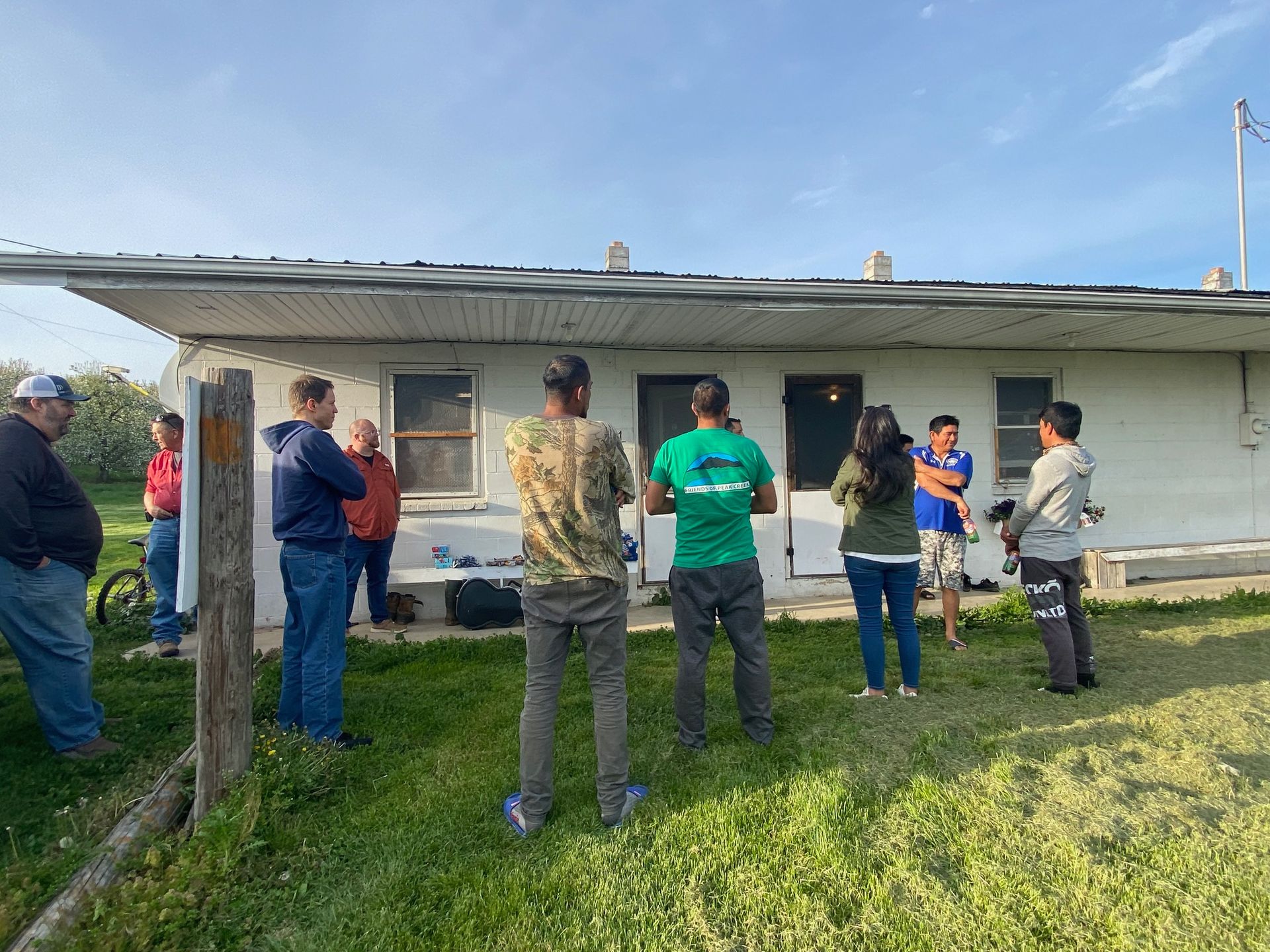 A group of people are standing in front of a white house.