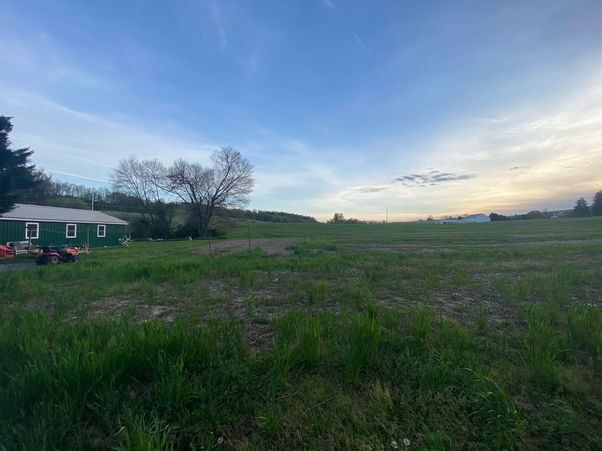 A green house is sitting in the middle of a grassy field.