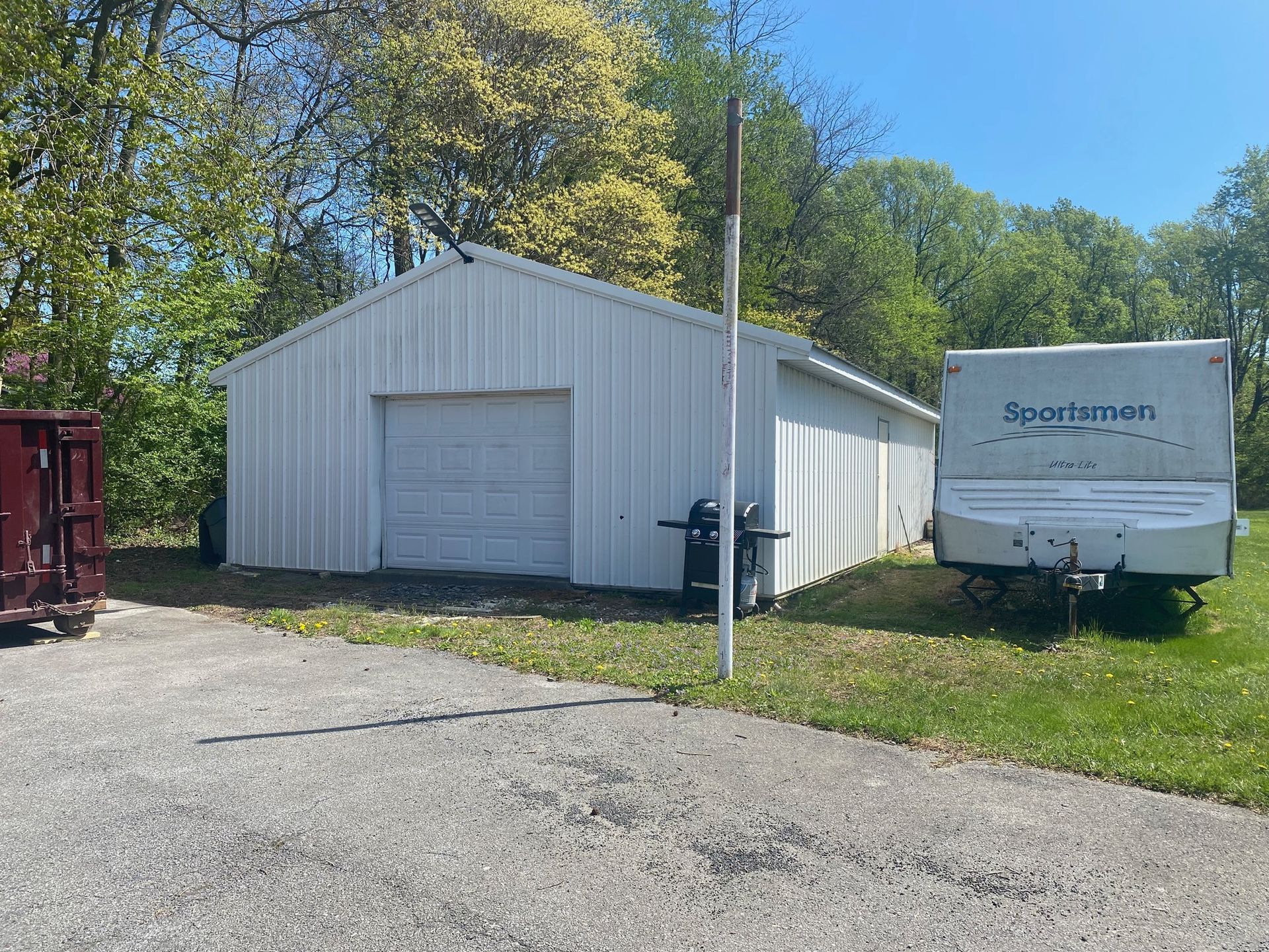 A white trailer is parked in front of a white garage.