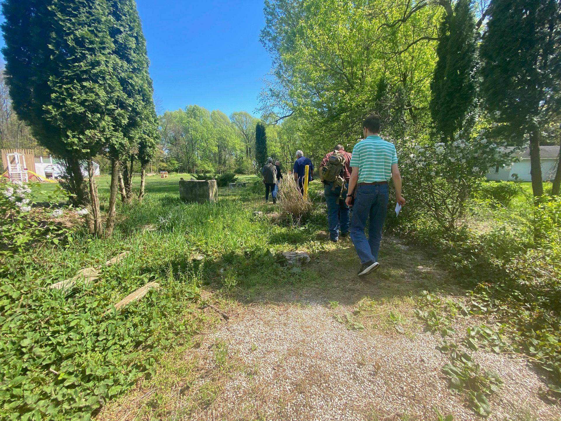 A group of people are walking down a dirt path in a park.