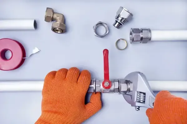 A person is working on a pipe with a wrench.