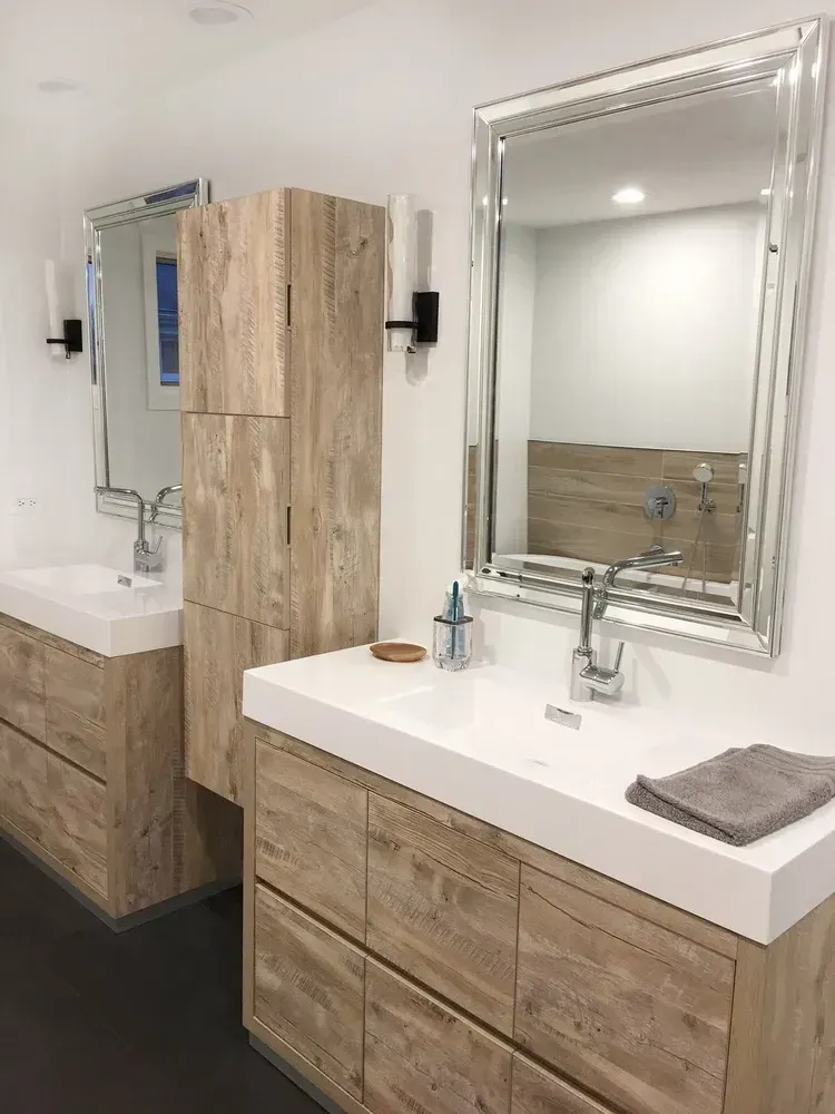Modern barrier free bathroom with wood vanity, large mirror, white sink, and matching tall cabinet.