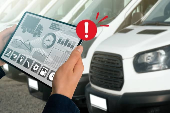 Hand holding a tablet with fleet management software beside a white delivery truck 