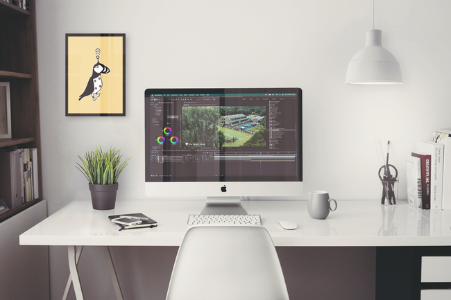 A white desk with a computer on it and a picture on the wall.