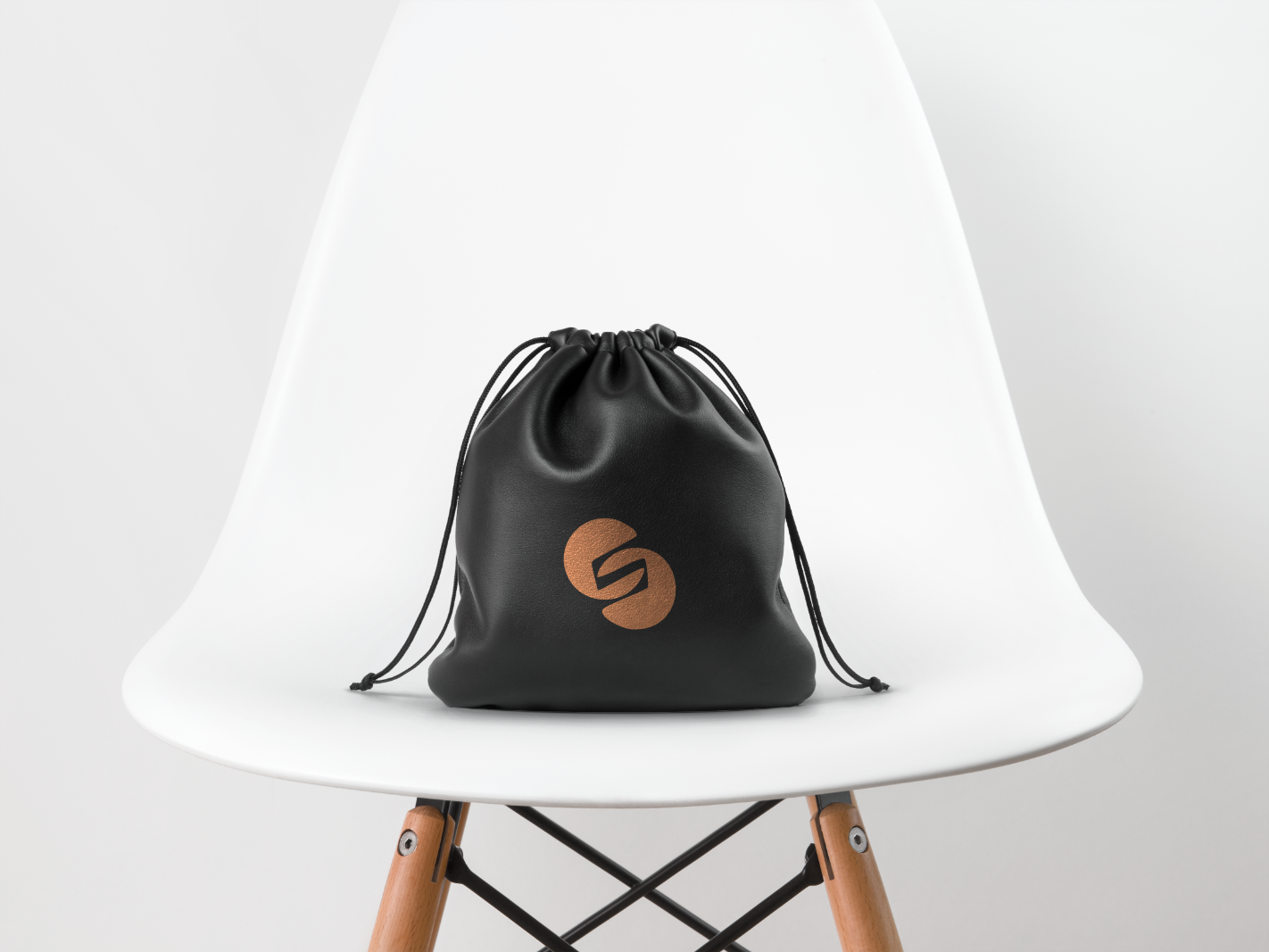 A black drawstring bag is sitting on a white chair.