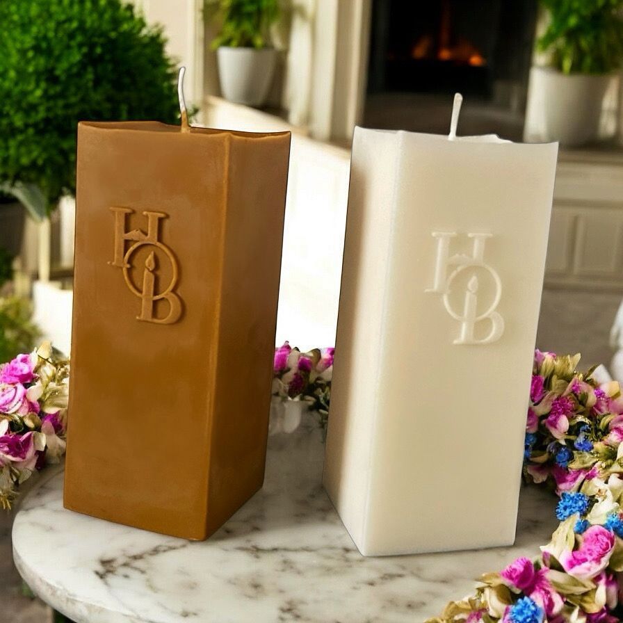 Two square candles with monograms on them are sitting on a table.