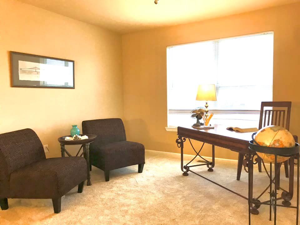 A room with two chairs and a desk with a globe on it
