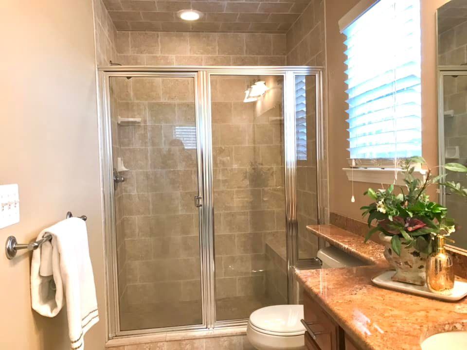 A bathroom with a walk in shower , toilet , sink and mirror.