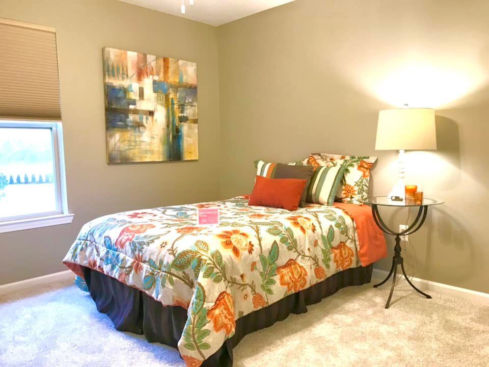 A bedroom with a bed a lamp and a painting on the wall