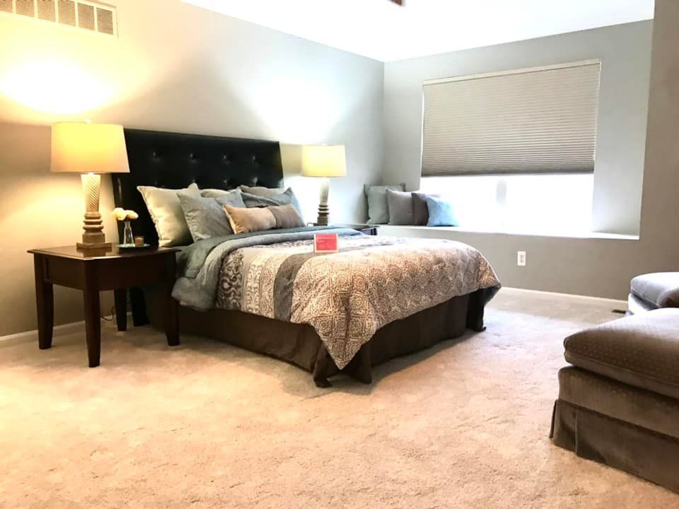 A bedroom with a bed , lamps , and a window seat.