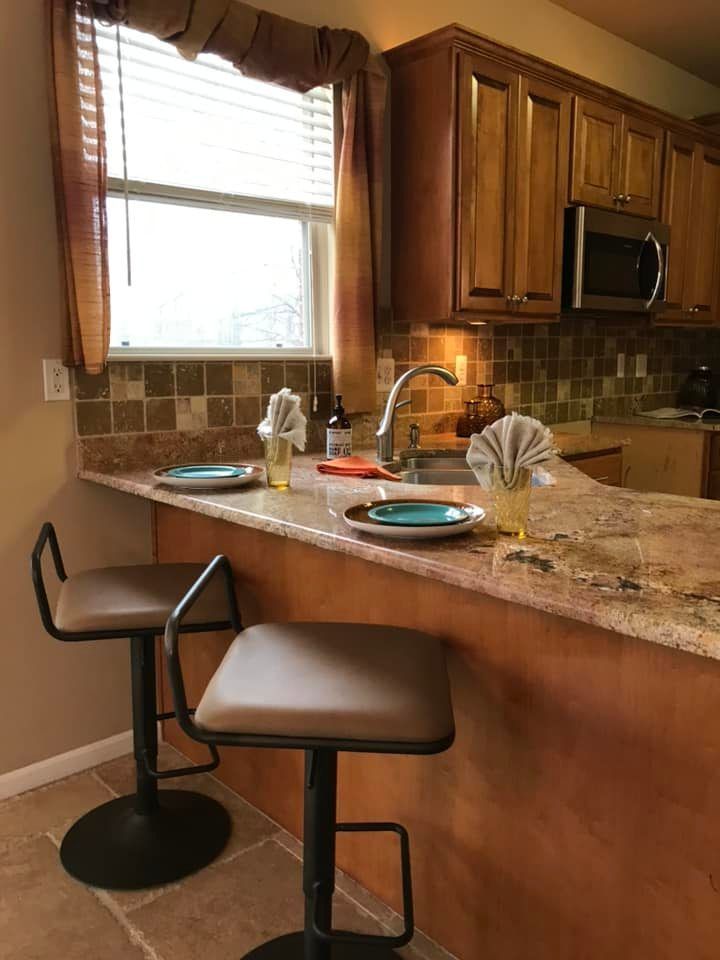 A kitchen with two bar stools and plates on the counter.