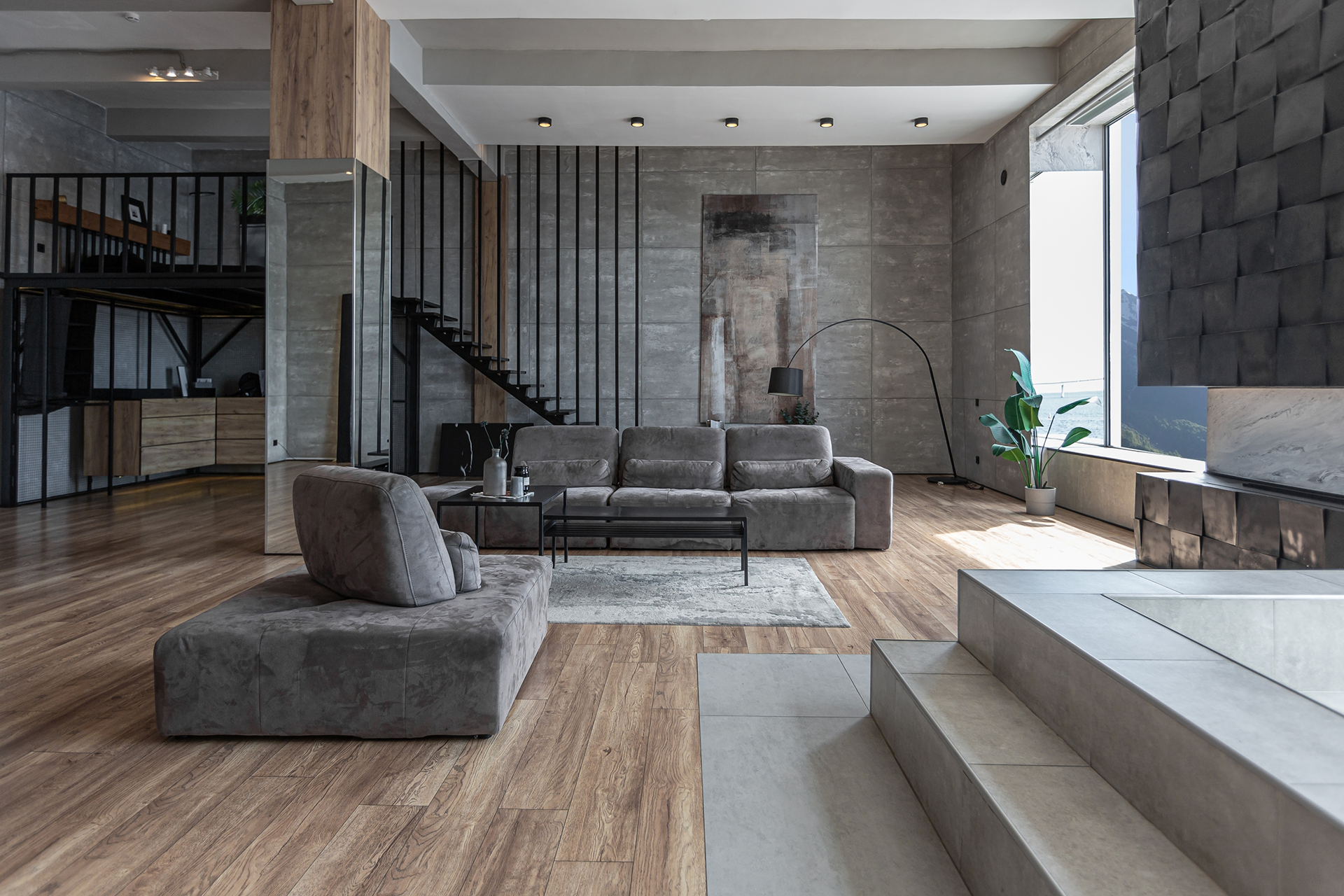 A living room with a couch , chair , coffee table and stairs.