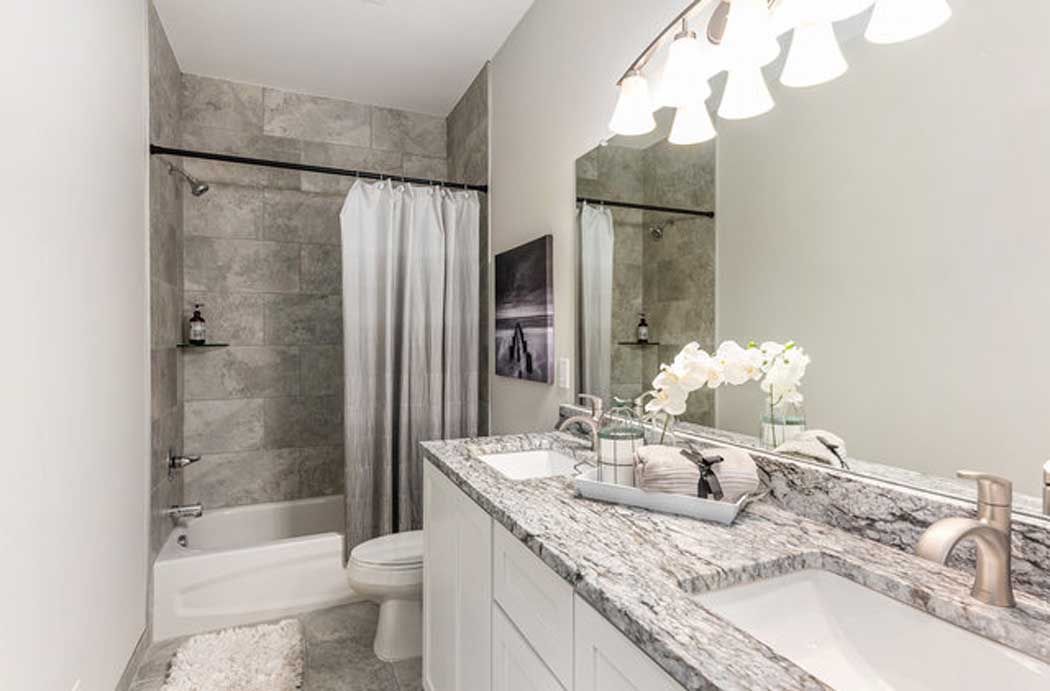 A bathroom with a sink , toilet , shower and mirror.