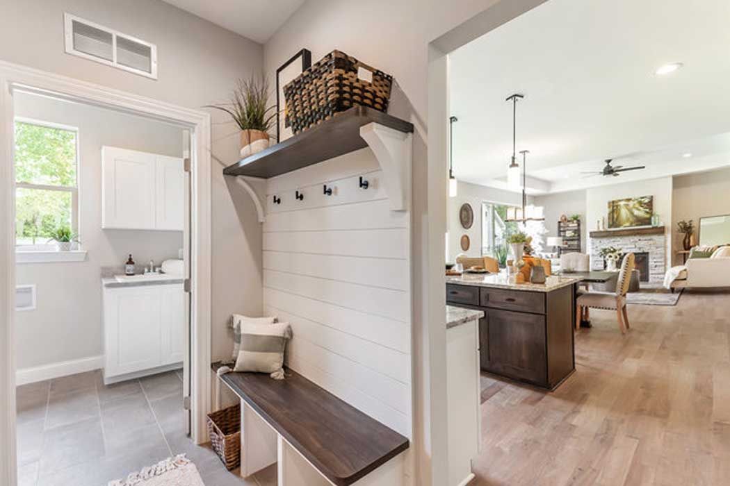 A hallway in a house with a bench and a shelf.
