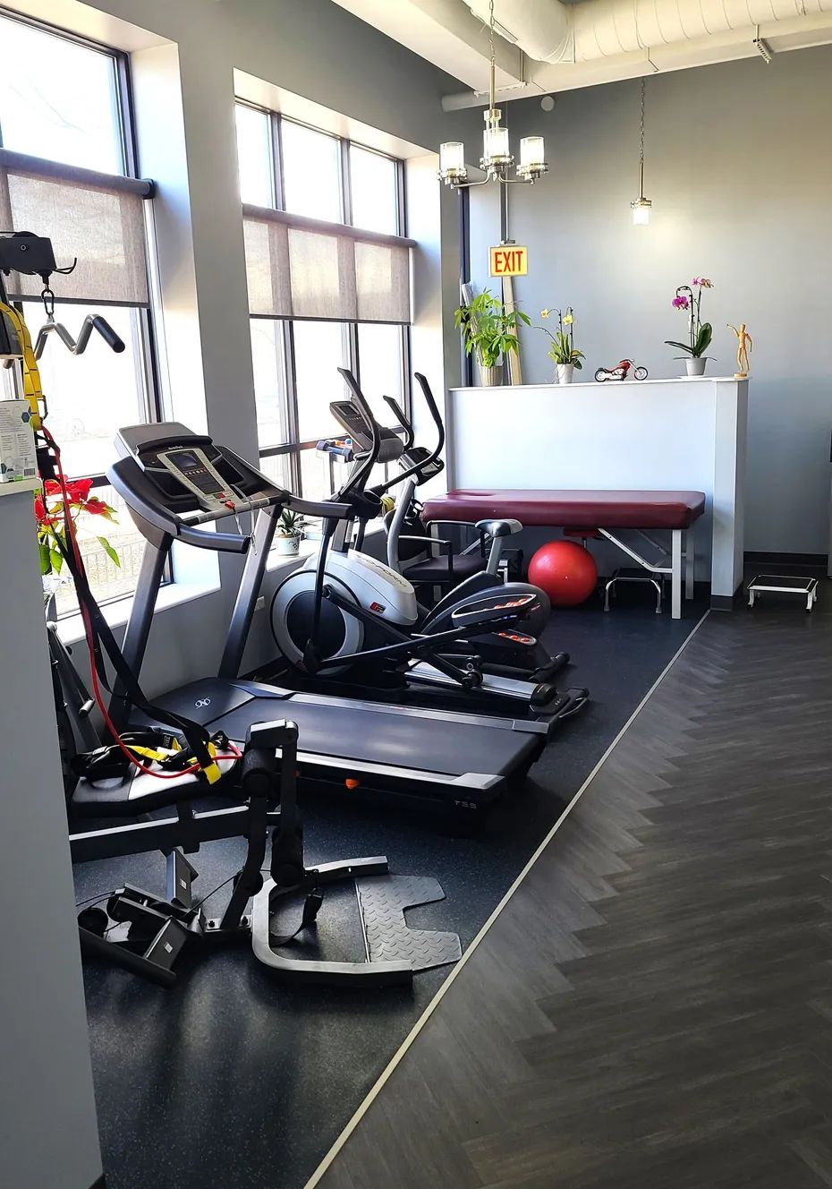 Gym interior with treadmills, elliptical, and exercise equipment near a window.