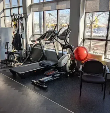A gym with exercise machines, a treadmill, elliptical, weights, and a red exercise ball.