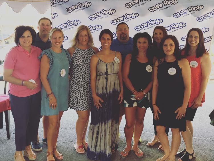 Group of people posing together in front of a backdrop with a logo.