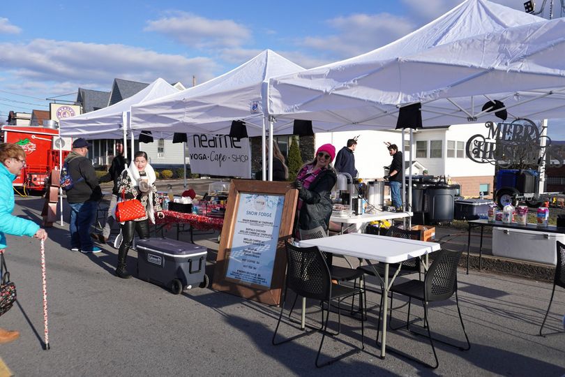 Outdoor market with white tents, people browsing and vendors selling food.