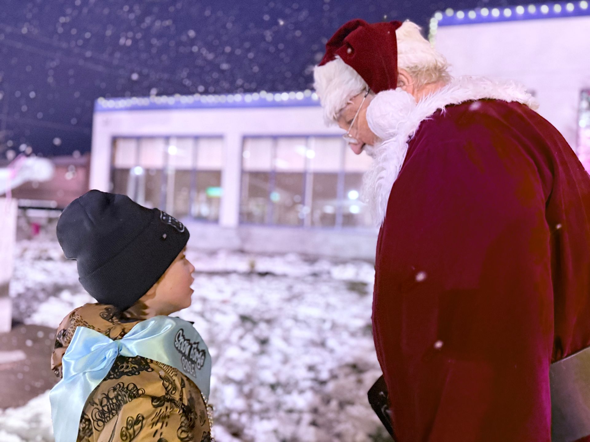 Santa and a little boy in front of the borough building.