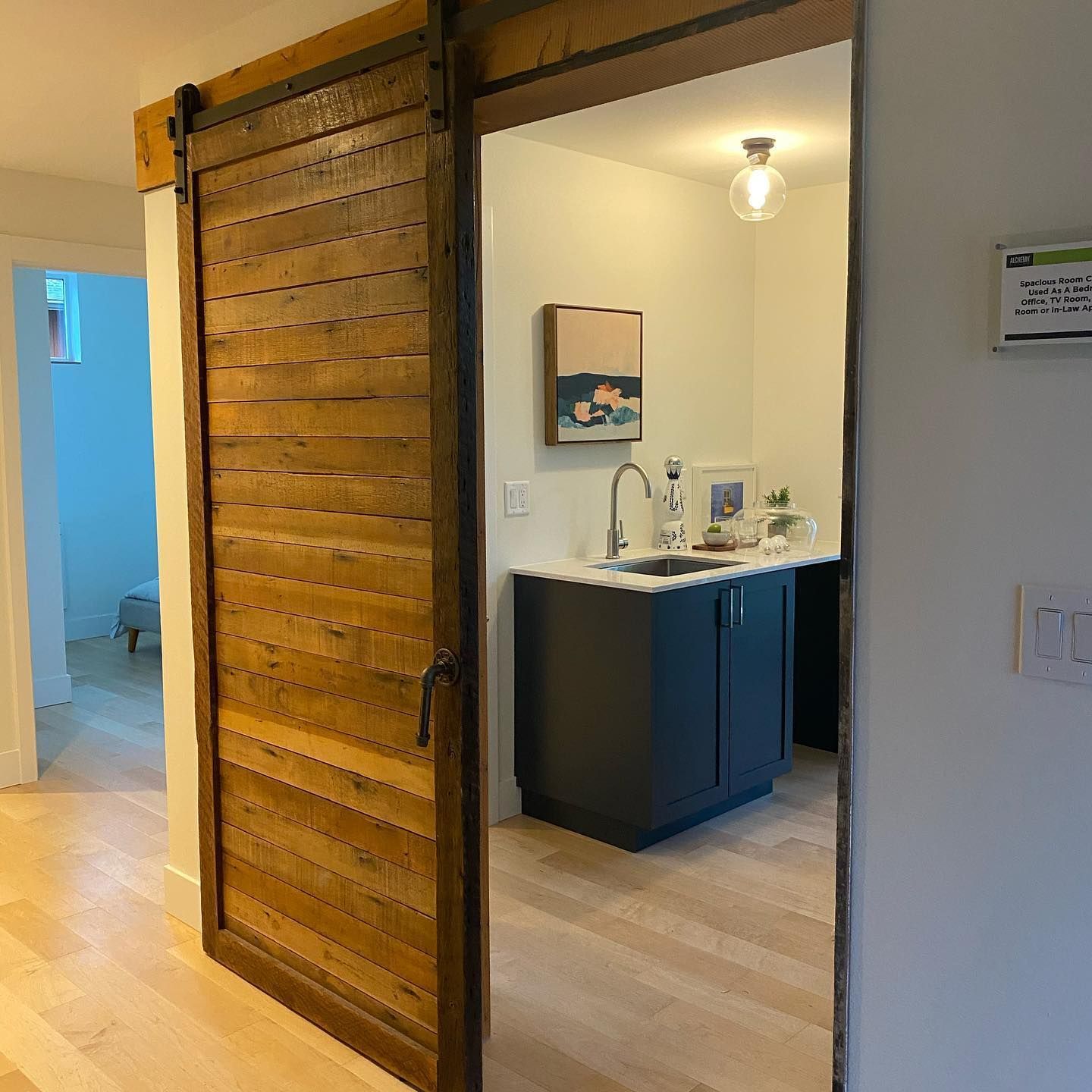 A wooden sliding door opens to a kitchen with a sink and cabinets.