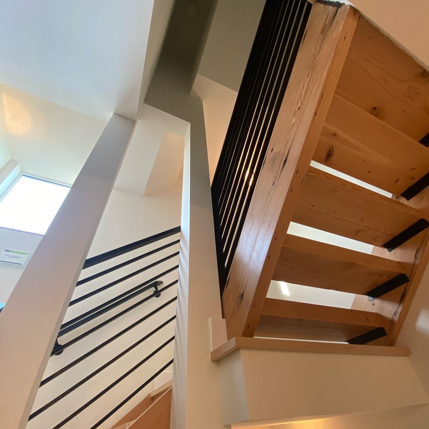 Looking up at a wooden staircase with a black railing