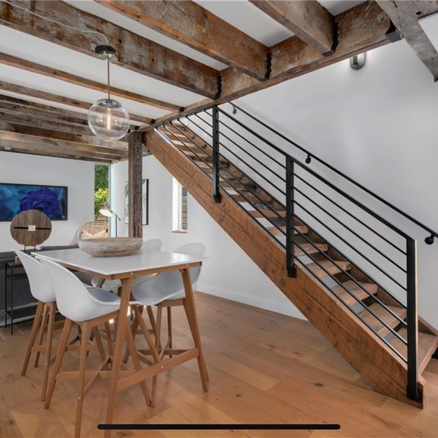 A dining room with a wooden staircase and a table and chairs